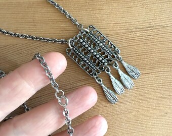 Collar colgante vintage de peltre con diseño rectangular intrincado y ornamentado.