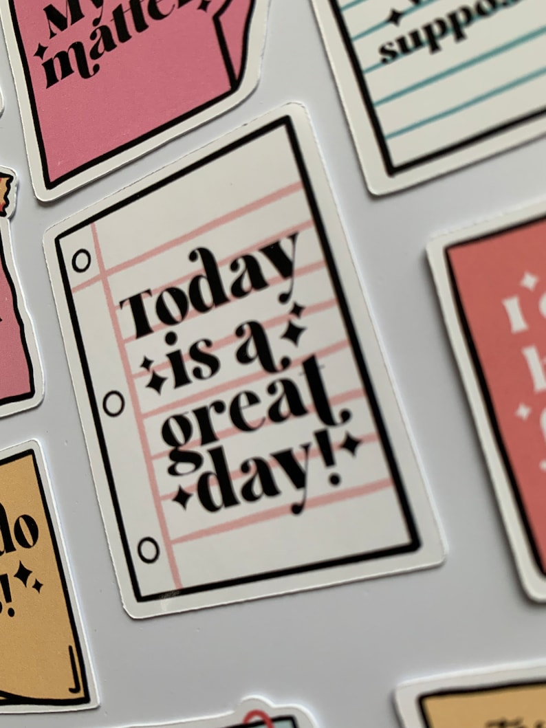 K&ouml;nnte beinhalten: Wei&szlig;er Aufkleber mit schwarzem Rand und rosa Linien. Der Aufkleber tr&auml;gt den Text "Today is a great day!" mit rosa Glitzerakzenten.