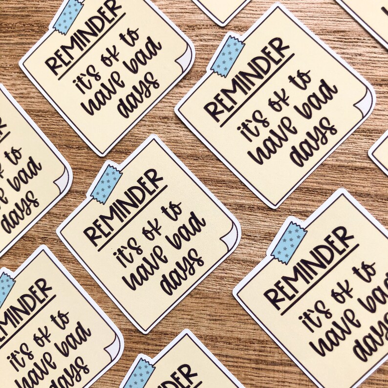 Puede incluir: Un conjunto de seis pegatinas de recordatorio amarillas con acentos de cinta azul. Cada pegatina dice "REMINDER it's ok to have bad days".