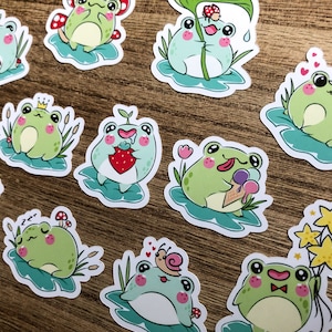 May include: A set of 10 frog stickers with various designs. The frogs are green with white eyes and are depicted in different poses, such as eating strawberries, holding ice cream cones, and sleeping. The stickers are on a wood background.
