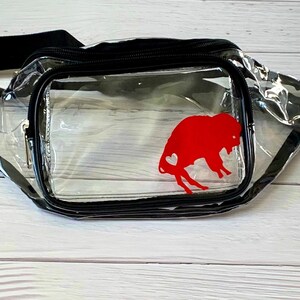 May include: Clear plastic fanny pack with a black adjustable strap and a red buffalo silhouette with a heart inside.