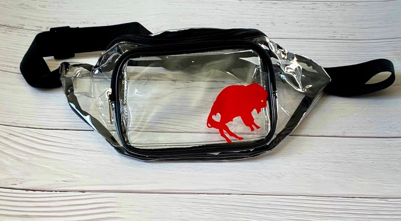 May include: Clear plastic fanny pack with a black adjustable strap and a red buffalo silhouette with a heart inside.