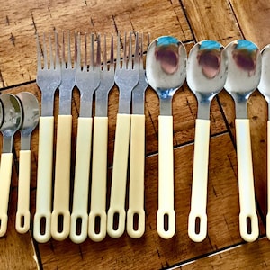 Op de afbeelding: Een set van 18 zilverkleurige bestekdelen met cr&egrave;mekleurige handvatten. De set bevat vorken en lepels.