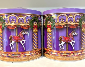 May include: Two purple and gold Christmas themed tin canisters with a carousel horse design. Each canister has a white horse with a red saddle and a wreath of holly and red bows.