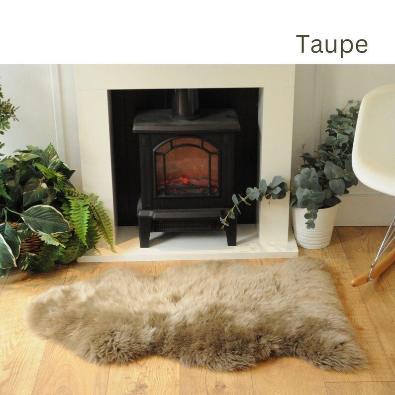 May include: A taupe faux fur rug in front of a fireplace. The rug is soft and fluffy, and it would be perfect for adding a touch of warmth and comfort to any room.