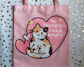May include: Pink tote bag with a cartoon calico cat and a heart with the text "no thoughts head empty".