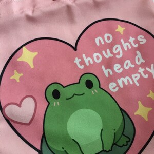 May include: Pink canvas tote bag with a heart-shaped design featuring a green frog and the text "no thoughts head empty".