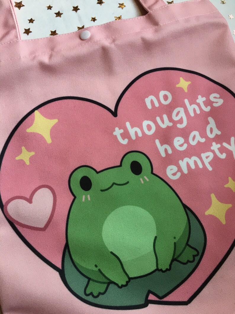 May include: Pink canvas tote bag with a heart-shaped design featuring a green frog and the text "no thoughts head empty".