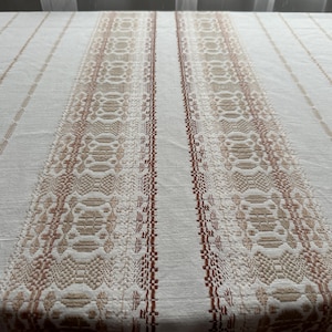 Peut inclure: Nappe crème avec des rayures verticales. Les rayures alternent entre une couleur crème unie et un motif en nuances de marron. Le motif comprend des formes géométriques et des lignes, créant un aspect texturé.