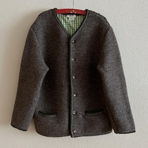 May include: A dark grey cardigan with a V-neck and button closure. It features two front pockets and a green and white checked lining. The trim and pocket edges are dark green. The cardigan is suspended on a red hanger.