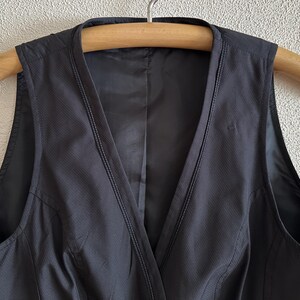 May include: A black sleeveless dress with a V-neckline and a fitted bodice. The dress is made of a smooth, lightweight fabric.