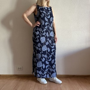Könnte beinhalten: Ein langes, ärmelloses Maxikleid mit Blumenmuster. Das Kleid ist marineblau mit einem hellblauen Blumenmuster. Das Kleid ist aus einem weichen, fließenden Stoff.