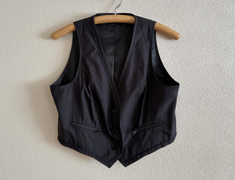 May include: A black sleeveless vest with a zipper closure and a button down front.