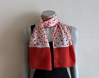 Peut inclure: Une écharpe à pois rouges et blancs avec une bordure rouge unie. L'écharpe est présentée sur un mannequin.