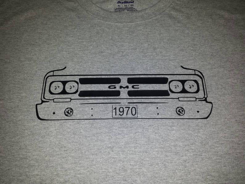 Puede incluir: Una camiseta gris con un contorno negro de una parrilla delantera de un cami&oacute;n GMC 1970. La parrilla tiene el texto "GMC" y "1970" impreso en ella.