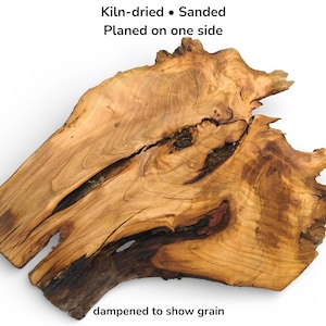 Könnte beinhalten: Eine kammergetrocknete, geschliffene und einseitig gehobelte Holzplatte mit natürlicher Waldkante. Das Holz weist eine ausgeprägte Maserung, dunkle Astlöcher und unregelmäßige Ränder auf. Text: Kiln-dried • Sanded, Planed on one side, dampened to show grain.