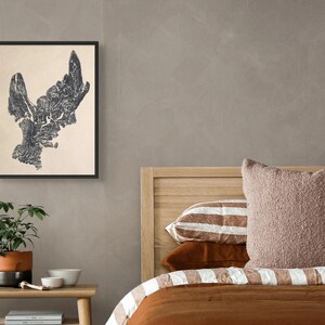 Könnte beinhalten: Ein gerahmter Wandkunstdruck mit einer dunklen, komplexen, abstrakten Illustration im Tusche-Stil auf hellcremefarbenem Hintergrund. Das Kunstwerk befindet sich in einem dünnen schwarzen Rahmen und hängt an einer neutralen Wand über einem Nachttisch aus Holz.