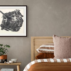 Könnte beinhalten: Ein quadratischer Schwarz-Weiß-Druck mit einem detaillierten Querschnittsmuster einer Holzmaserung, eingefasst in einen dünnen schwarzen Rahmen. Das Kunstwerk zeigt komplexe organische Ringe und Texturen in hohem Kontrast auf einer neutralen Wand.