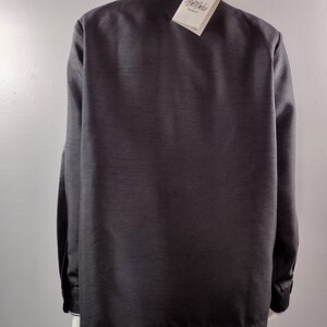 May include: A black long-sleeved shirt with a white collar and a white tag that says "Bellerose" on it.