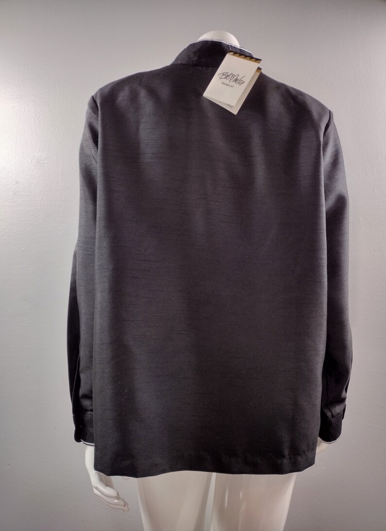 May include: A black long-sleeved shirt with a white collar and a white tag that says "Bellerose" on it.