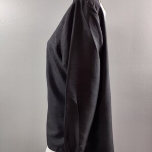May include: A black long-sleeved shirt with a white collar and cuffs. The shirt has a slightly loose fit and is made of a smooth, silky fabric.
