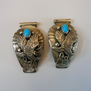 May include: A pair of silver watch band clasps with turquoise stones and an eagle design.