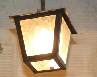 May include: A black metal hanging light fixture with a frosted glass shade. The light is on and illuminating the room.