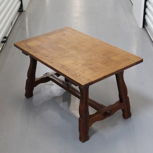 May include: A rustic wooden coffee table with a rectangular top and intricate, carved legs. The table is made of dark brown wood and has a natural finish.
