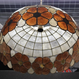 May include: A brown and white stained glass lampshade with a floral design. The lampshade is made of many small pieces of glass that are arranged in a pattern of flowers. The lampshade is round and has a white interior.