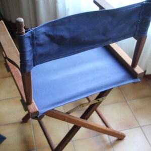 May include: A wooden folding chair with a blue canvas seat and back. The chair is made of dark wood and has a simple design.