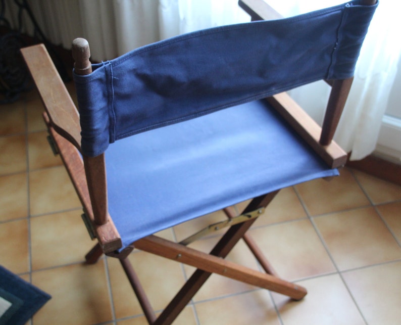 May include: A wooden folding chair with a blue canvas seat and back. The chair is made of dark wood and has a simple design.