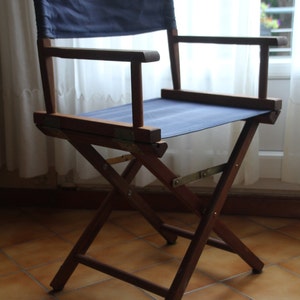 May include: A wooden folding chair with a blue canvas seat and back. The chair is made of dark wood and has a simple design.