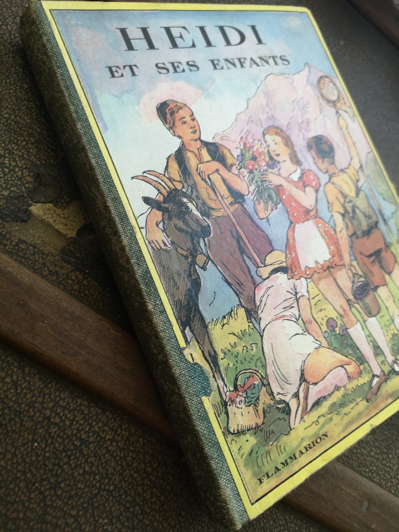 Może przedstawiać: Okładka starej książki z tytułem "HEIDI ET SES ENFANTS" w ż&oacute;łtych literach na zielonym tle. Okładka przedstawia ilustrację dzieci i kozy w g&oacute;rzystym krajobrazie.