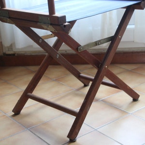 May include: A wooden folding chair with a dark blue canvas seat. The chair is made of dark brown wood and has a simple, classic design.