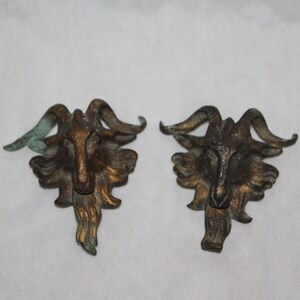 May include: A pair of antique bronze goat head door or cabinet pulls. The goat heads are detailed with horns, fur, and a textured finish.