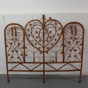May include: A brown wicker headboard with a heart-shaped central panel and two arched side panels. The headboard features detailed scrollwork and a decorative design. The headboard is approximately 127 cm high and 152 cm wide.