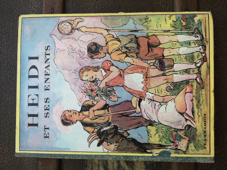 Może przedstawiać: Okładka starej książki z kolorową ilustracją dzieci na polu. Tytuł książki to "HEIDI ET SES ENFANTS" na ż&oacute;łtym tle.