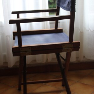 May include: A wooden folding chair with a blue canvas seat. The chair is made of dark wood and has a simple design.