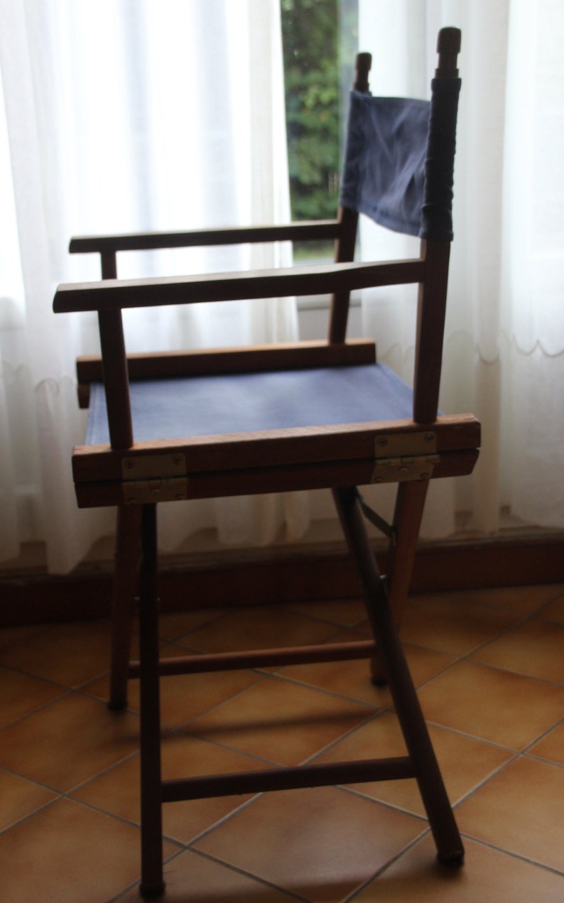 May include: A wooden folding chair with a blue canvas seat. The chair is made of dark wood and has a simple design.