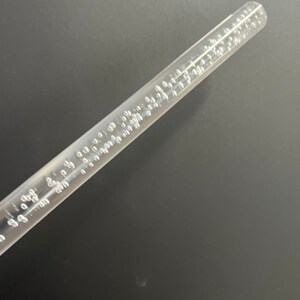 May include: A clear plastic wand with small air bubbles embedded throughout. The wand is approximately 12 inches long.