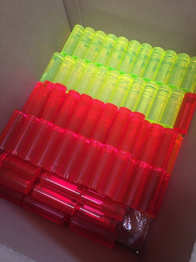 May include: A box filled with bright red and green plastic tubes. The tubes are stacked in rows and are all the same size.