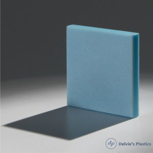 May include: A light blue, square-shaped piece of plastic. The object is standing upright, casting a shadow on a white surface. The logo for Delvie's Plastics is in the bottom right corner.