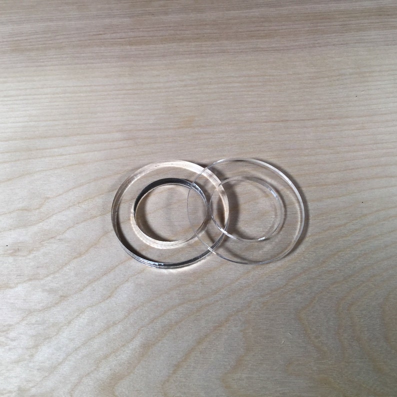 May include: Two clear plastic rings, one slightly larger than the other, are stacked on top of each other.