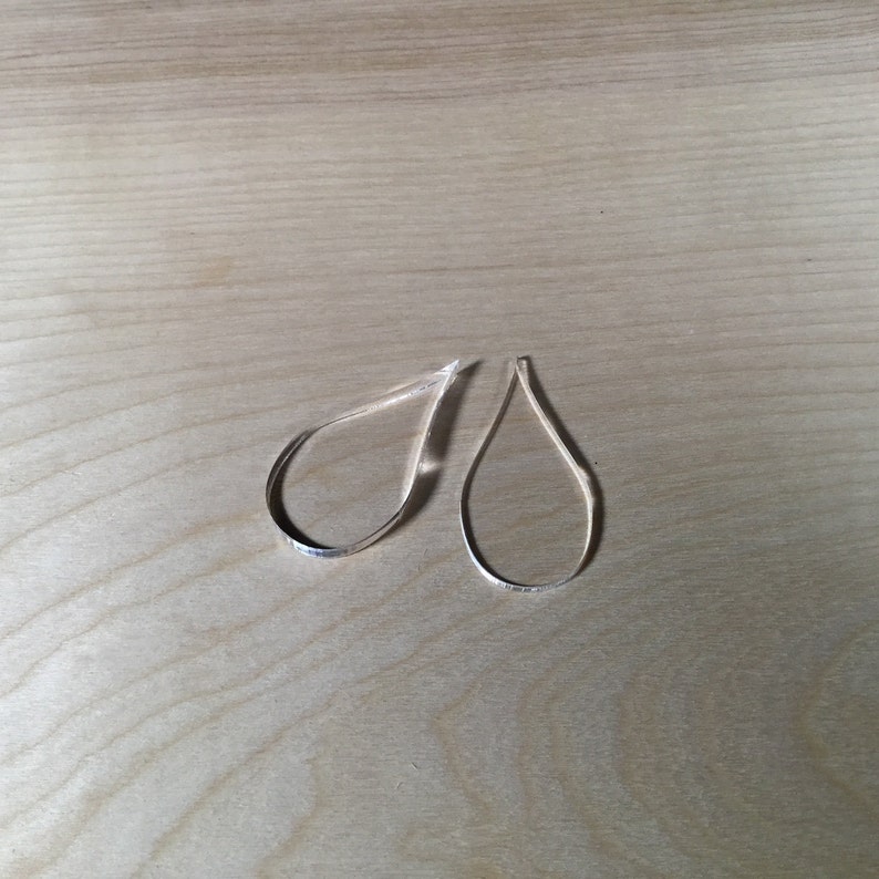 May include: A pair of silver teardrop-shaped earrings.