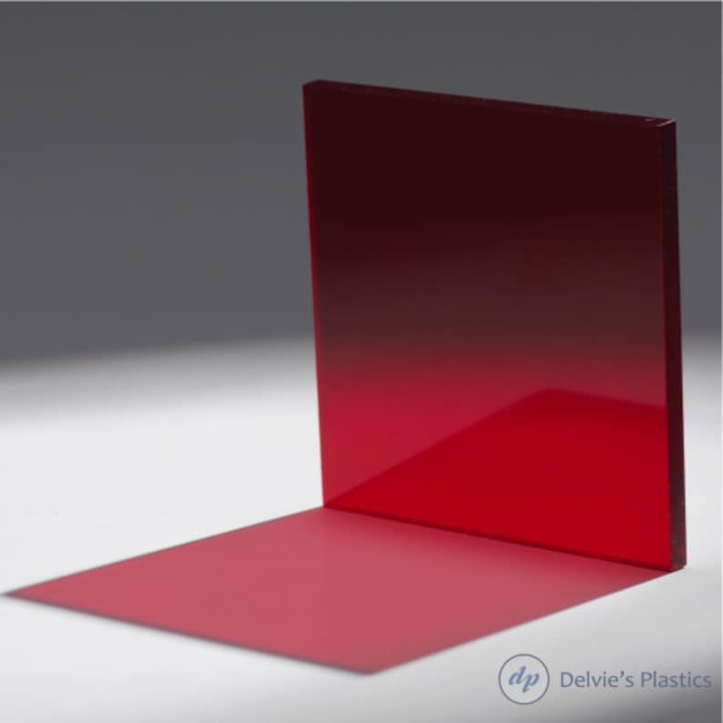 Puede incluir: Una l&aacute;mina de acr&iacute;lico roja con un efecto degradado, pasando de un rojo m&aacute;s oscuro en la parte superior a un rojo m&aacute;s claro en la parte inferior. La l&aacute;mina est&aacute; de pie sobre una superficie blanca, proyectando una sombra.