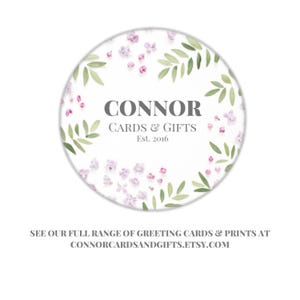 May include: A white circle with a floral design featuring green leaves and pink flowers. The text "CONNOR CARDS & GIFTS Est. 2016" is in the center of the circle.
