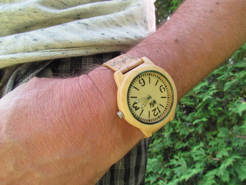 Puede incluir: Un reloj de pulsera de madera con una correa marr&oacute;n claro y una esfera marr&oacute;n claro. La esfera tiene n&uacute;meros y manecillas negros, y la palabra "PIM" est&aacute; impresa en el centro.