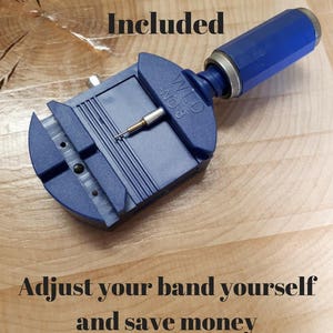 Op de afbeelding: Blauw metalen horlogeband-verwijderingsgereedschap met een blauwe handgreep. Het gereedschap ligt op een houten oppervlak. De tekst "WLD NO.8" is zichtbaar op het gereedschap. De tekst "Link Removal Tool Included" staat bovenaan de afbeelding. De tekst "Pas uw band zelf aan en bespaar geld" staat onderaan de afbeelding.