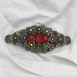 Vintage Art Deco-brosch med dubbla klänningsspännen och rubinfärgad strass. 8 cm.