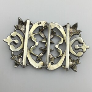 May include: Silver filigree buckle with a decorative design. The buckle is marked with the number "83" on the back.